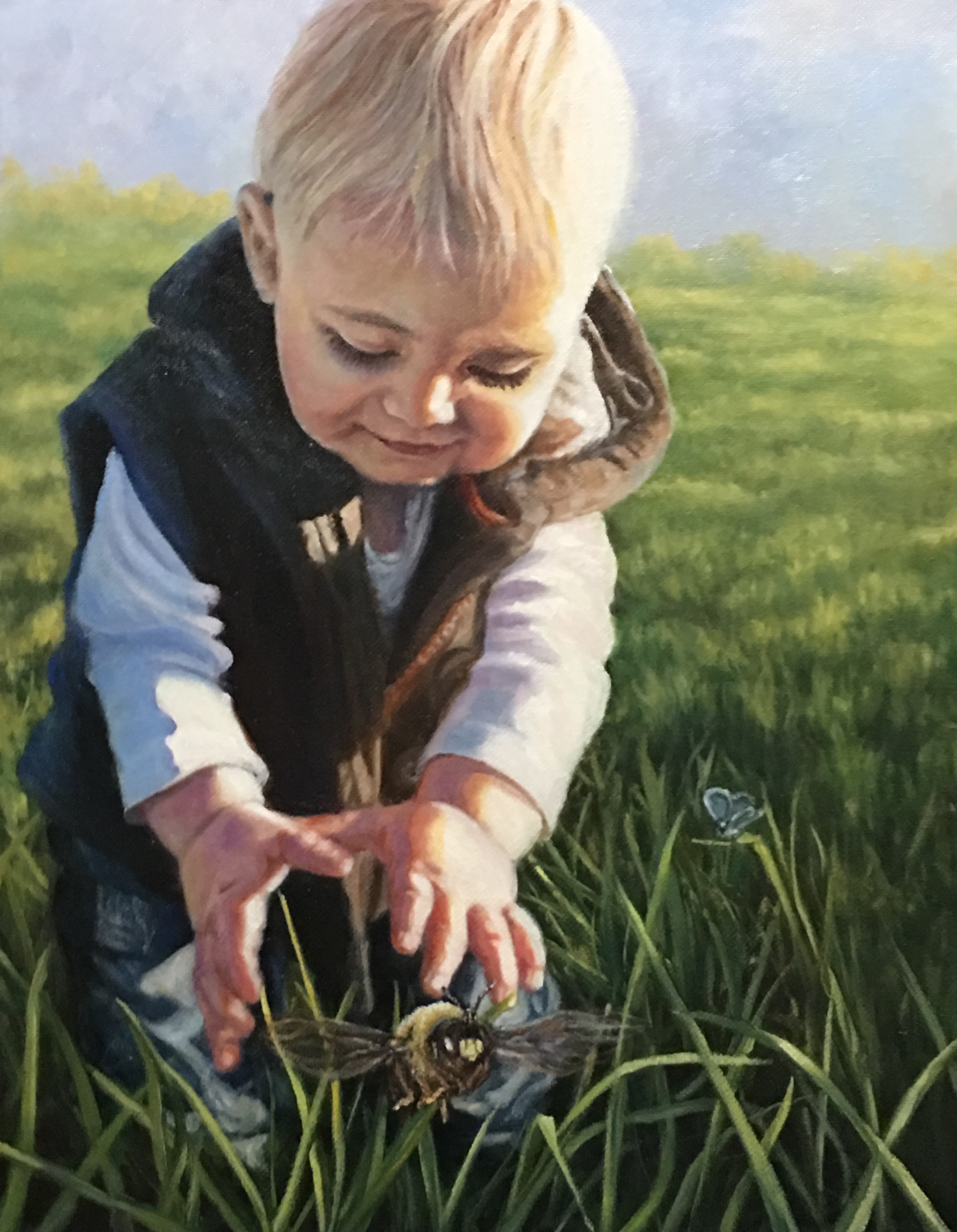 Young child reaching toward a bumblebee in grass